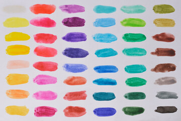 A top-down shot of a grid of watercolor swatches in various colors on a white background, demonstrating a range of hues and textures