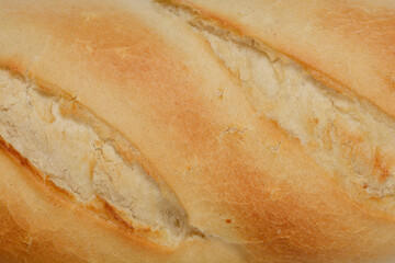 A close-up, horizontal shot of a plain white bread roll with diagonal cuts, showcasing its texture and golden crust