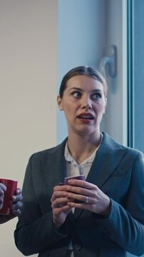 Vertical Screen: Two colleagues share a conversation while gossiping about a third coworker, who remains unaware. Concept of workplace gossip, office dynamics, and informal communication