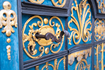 A beautifully decorated metal door handle against the background of a blue door.
