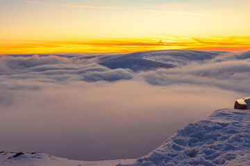 Zachód słońca w polskich górach Karkonosze na Śnieżka, po zmierzchu ponad chmurami.