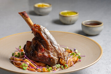Lamb chop with noodles, sauce and mustard on a gray background