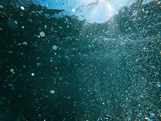 Underwater air bubbles in clean blue ocean water as natural background, low angle view