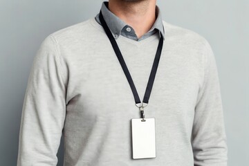 Male wearing id badge on lanyard over grey sweater.
