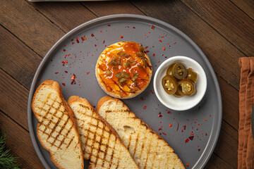 Portion of baked brie with jalapeno pepper and toast on wooden table