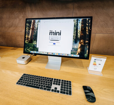 Paris, France - Feb 18, 2025: An Apple Mac Mini paired with a Studio Display, a wireless Magic Keyboard, and a Magic Mouse is showcased on a wooden desk, featuring a clean and modern setup.