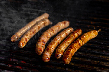 Grilling sausages on the grill with flames and smoke.
