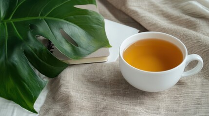 A tranquil workspace featuring a fresh cup of tea beside a leafy plant and a notebook, creating an inviting atmosphere for reflection and productivity.