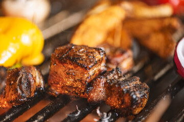 roasted meat and vegetables on the grill with flames and vegetables, close up