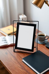 Elevated desk scene: a black frame takes center stage amid books, coffee, and a warm desk lamp glow.