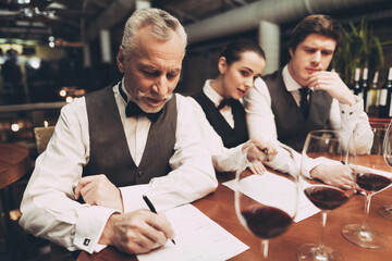 Confident elegant sommelier makes wine list in restaurant. Wine tasting.