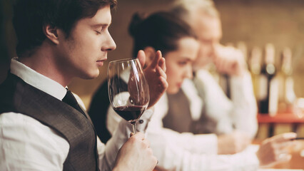 Professional sommelier tastes red wine in restaurant. Sommelier checks aging of wine.