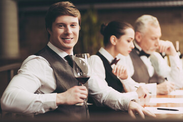 Professional sommelier tastes red wine in restaurant. Sommelier checks aging of wine.
