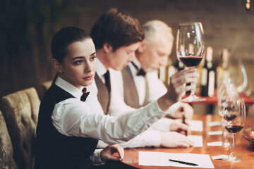Experienced sommelier woman explores taste of wine in restaurant. Wine tasting. Checking taste, color, sediments of wine
