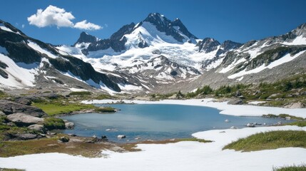 Fototapeta premium Alpine lake nestled in a snow-capped mountain range under a blue sky.
