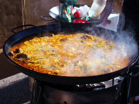Steaming Hot Traditional Spanish Paella Cooking Over an Open Fire in a Large Pan at Outdoor Market