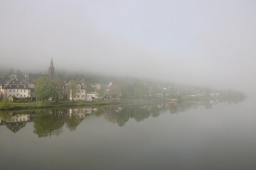 Naklejka premium Berncastel Wehlen liegt vreschlafen im Nebel am frühen Morgen am Fluss Mosel im Frühling