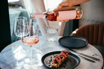 Pouring rose wine at a dinner party with friends in a bar or restaurant.