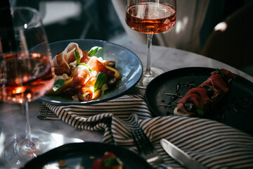 A table served for a dinner with prosciutto salad and rose wine in a bar or restaurant.