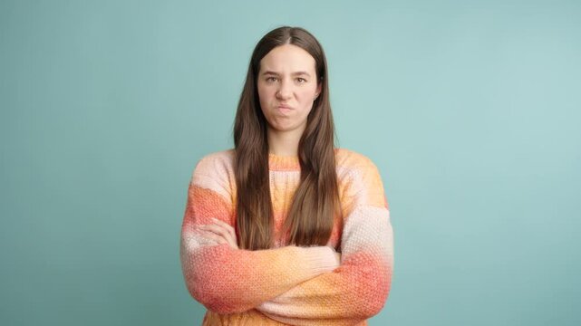 Woman expressing disgust with crossed arms on turquoise background