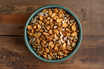 Healthy roasted seeds in a ceramic bowl resting on a wooden table
