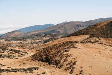Panoramic view of a desolate, yet beautiful landscape.  Rugged, rocky mountains stretch to the horizon under a clear sky. A sense of adventure and vastness fills the scene.