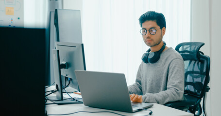 Young adult Asia male freelance eyeglasses typing write prompt AI bot IT app smart program nomad, video game, terminal with coding, user interface, designer, big data center on desktop computer.