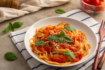 Spaghetti with fresh tomatoes sauce in white plate.topped with parmesan cheese and basil.