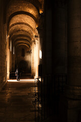 Fototapeta premium Suora che cammina in una navata illuminata dalla luce del sole.