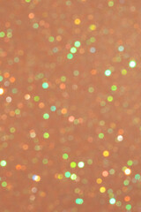 Abstract defocused light background with multicolored bokeh dots on gold