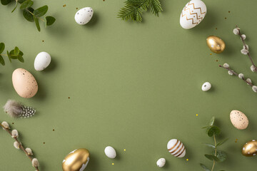 Easter-themed flat lay with decorated eggs, greenery, and feathers arranged aesthetically on green...