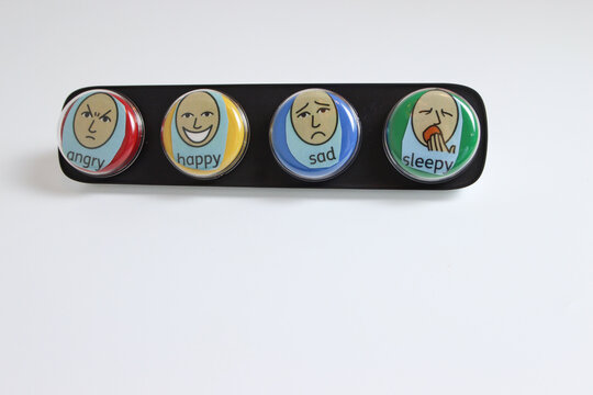 communication aid, set of four coloured switches to help non verbal people indicate emotions, happy, sad, sleepy or angry. on a white background with room for text