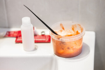 Hair dyeing at home. Woman dyes her hair red. Brush for dyeing hair in red dye. Ammonia-free dye. Hair dyeing in the bathroom at home.