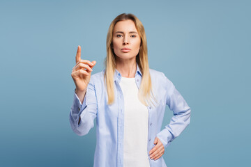 Confident businesswoman raising index finger on blue background