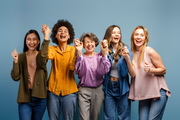Five cheerful women holding hands and laughing out loud celebrating victory