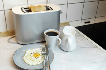 Breakfast served on the kitchen table with a fried egg on a plate and fresh bread and coffee