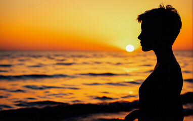 Fototapeta premium A woman’s silhouette standing by the ocean, watching the sunset