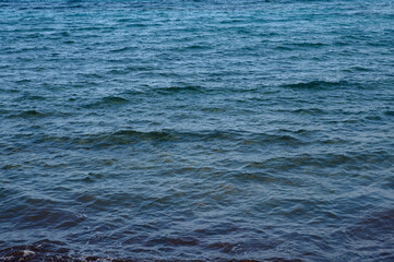 Tranquil waves gently ripple over the serene blue waters of a secluded beach at sunset