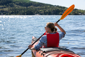 Woman in kayak back view. Happy young woman floating in transparent kayak on the crystal clear sea. Summer holiday vacation and cheerful female people relaxing having fun on the boat