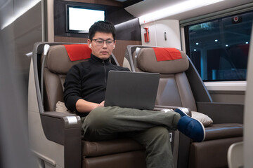 asian male working in high speed train with laptop