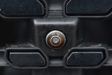 Scratched front parking camera lens closeup, visible damage. Cloudy front parking camera lens with scratches and scuff marks, impact of daily wear and tear on automotive components. Selective focus