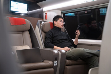 asian man using smart phone in high speed train in china