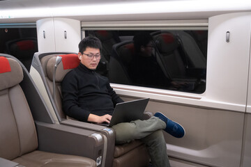 asian male working in high speed train with laptop