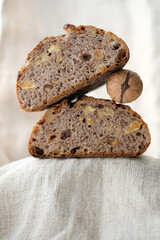Walnut raisin sourdough bread on a hemp coarse cloth. Pyramid of bread and walnut. Copy space. Shallow depth of field.