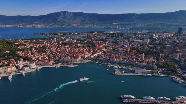 Aerial view of Split, Croatia. Cityscape of coastal touristic city with harbor filled with boats and mountains in background. Old town with historical red roof tiled buildings near Adriatic Sea