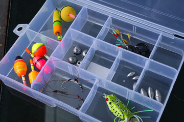 Fishing equipment such as floats, sinkers, hooks and fishing bait in a box.