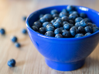 Fresh blueberries in a blue bowl. Sweet tasty blueberries on a wooden background. Concept for healthy eating and nutrition