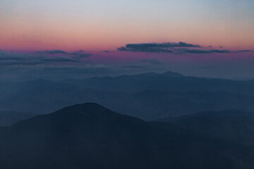 Obraz premium dark silhouettes of mountain peaks against a purple sky after sunset