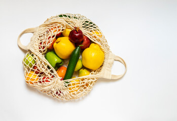 White string bag with different vegetables and fruits on a white background. top view.