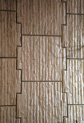 The wall is clad with light carved relief stone close up.